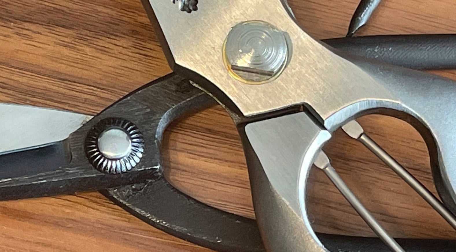 Close-up of Japanese garden shears showing a traditional kashime rivet pivot beside a bolt-and-nut pivot.