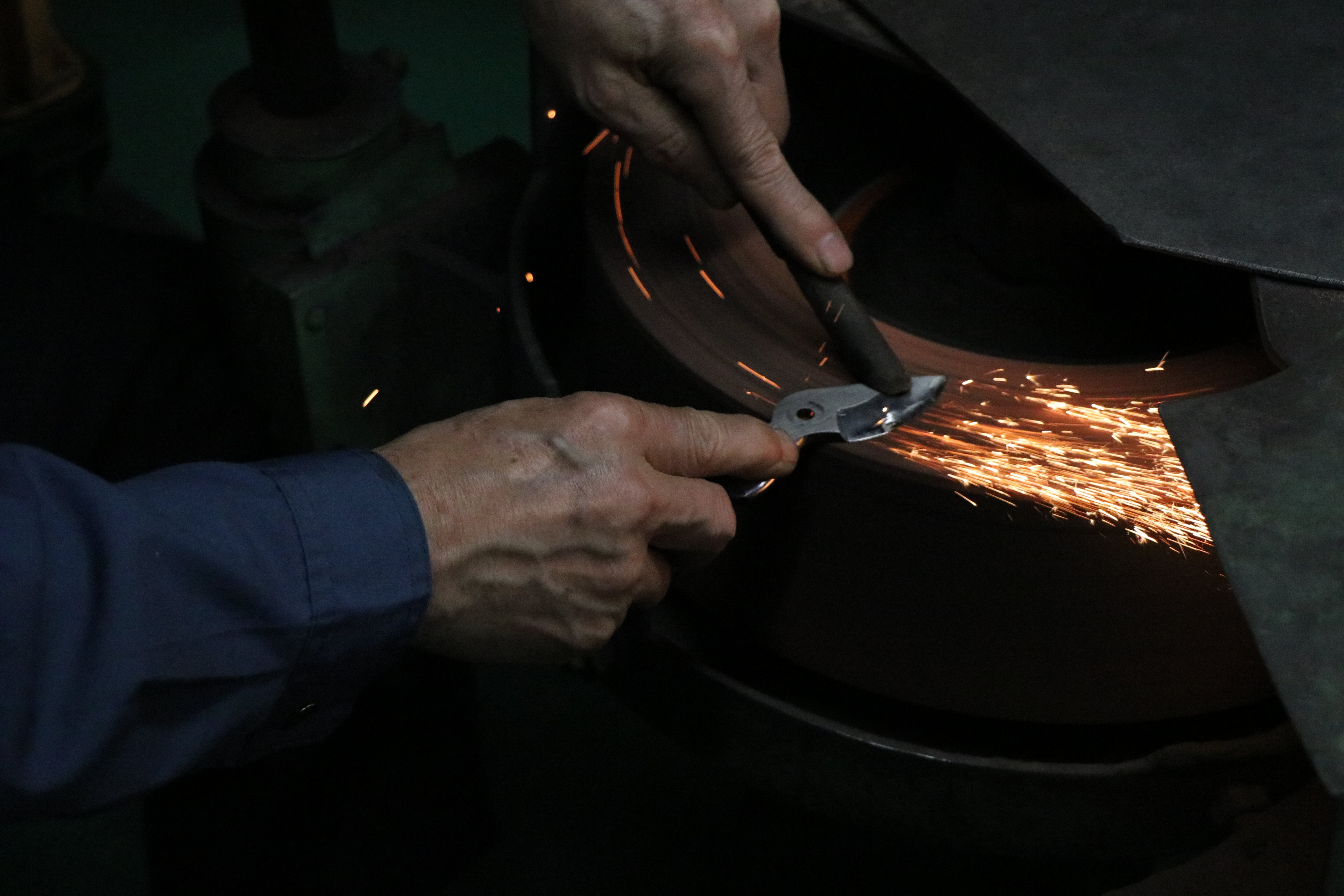 Master artisan meticulously hand-finishing the blade of a Toyama Hamono shear for optimal performance.