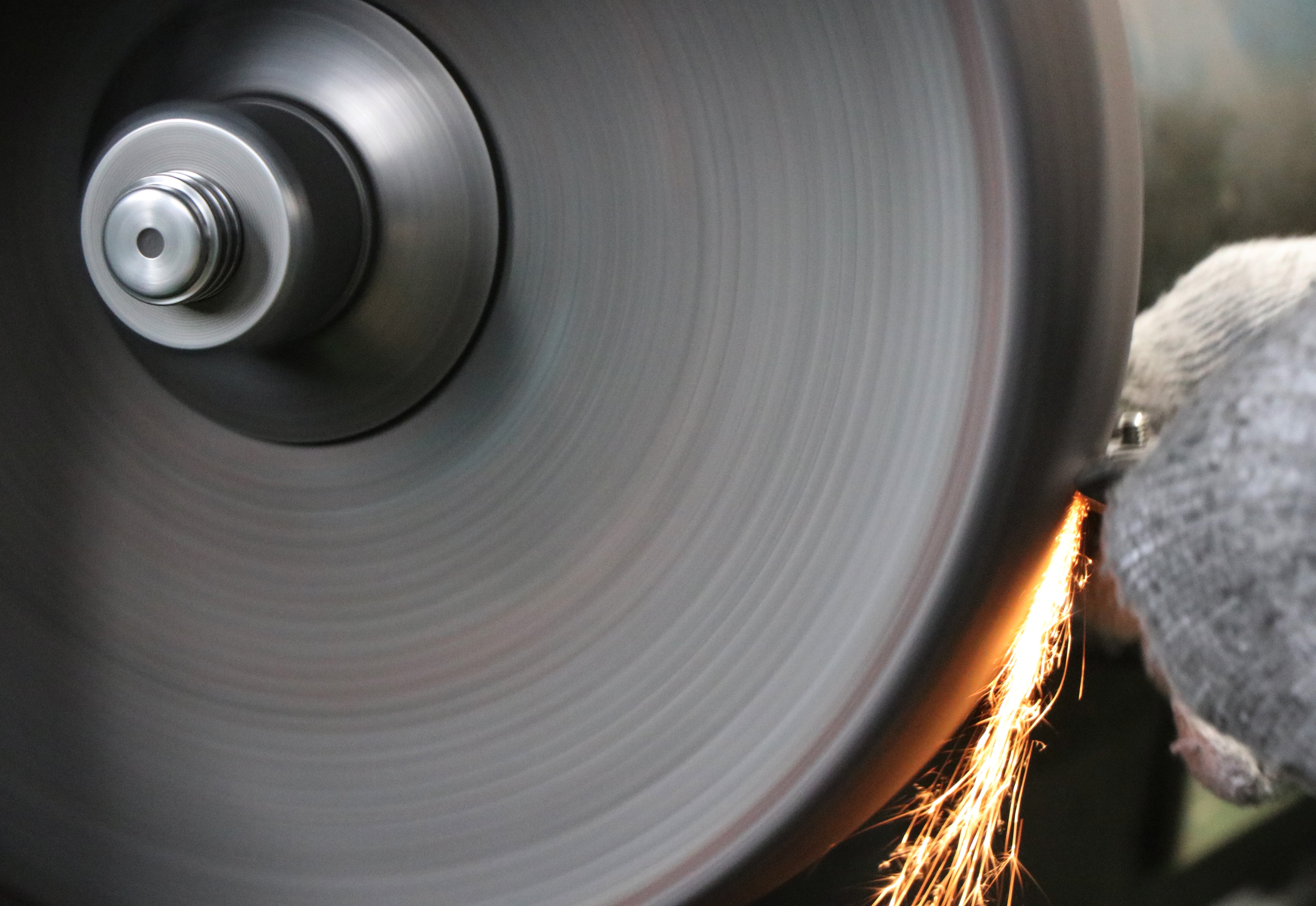 rtisan performing back hollow grinding on a Toyama Hamono blade, creating sparks for a sharp edge.