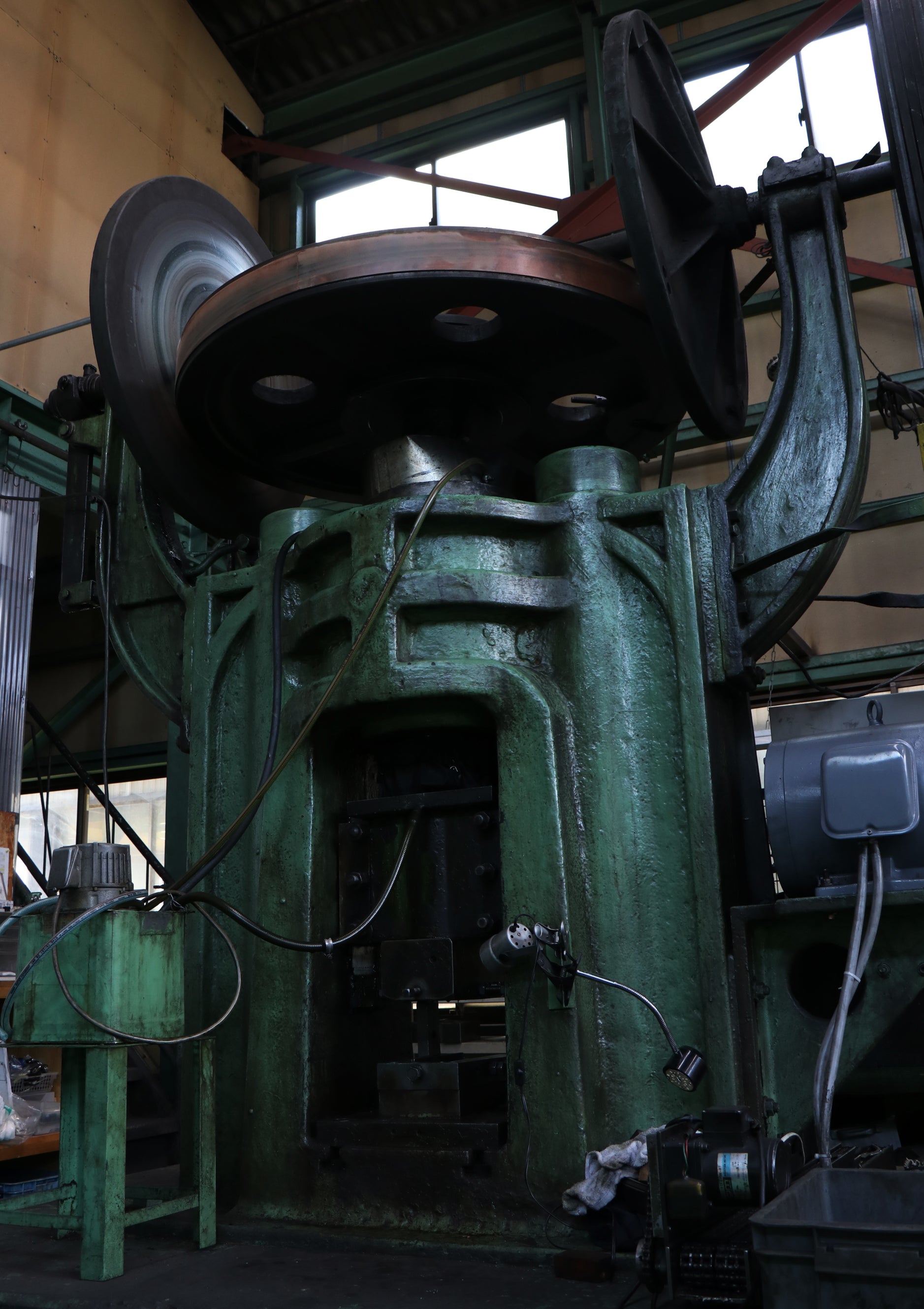 Large, green industrial mechanical power press in Toyama Hamono factory
